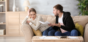 Man chastising a woman about finances while looking at spreadsheets and paperwork