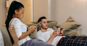 Couple in their pajamas on the couch calculating costs for a budget