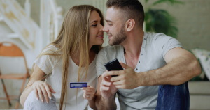 Couple sharing finances with the woman holding a credit card and nuzzling her partner