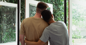Couple hugging while looking out an open window