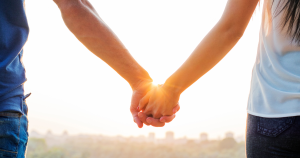 Close up of a couple holding hands in the sun