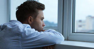 Man resting his head in his arms looking out the window