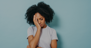 Woman looking irritated and defensive standing against a blue wall