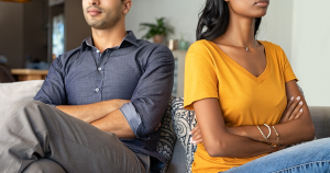 Closeup of a couple with their arms folded looking annoyed sitting next to each other