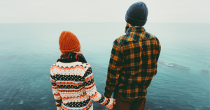 Couple standing on a cliff looking over the ocean